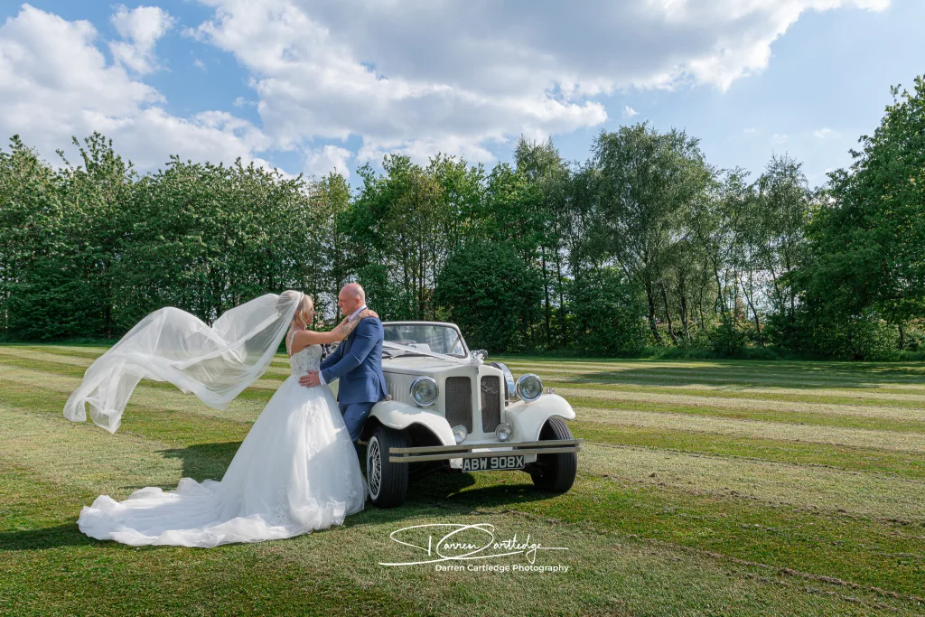 Wedding photographer captures bride and groom with wedding car in West Yorkshire.