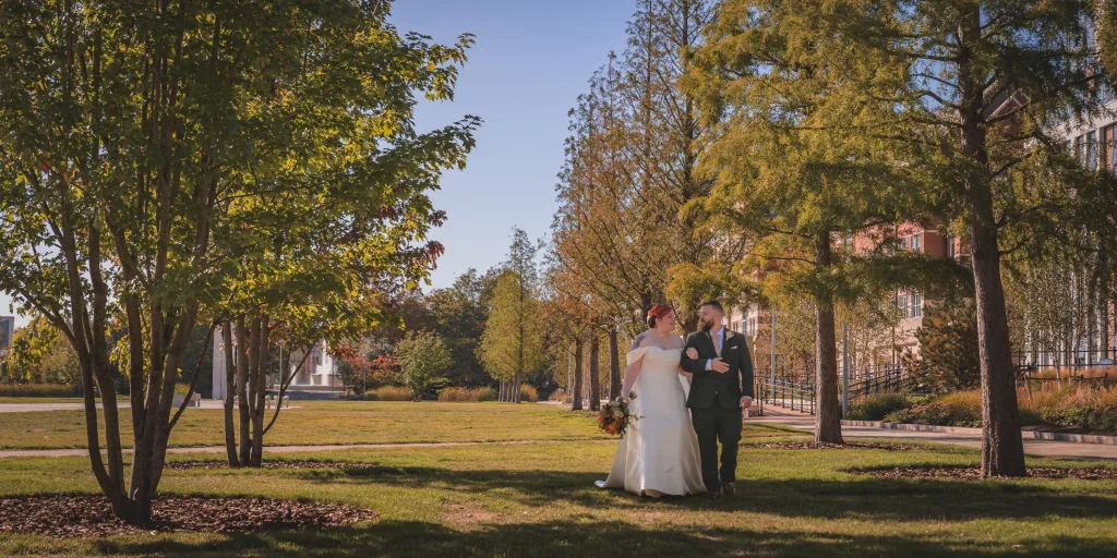 Bride and groom walking together through Queens Gardens in Hull on their wedding day.