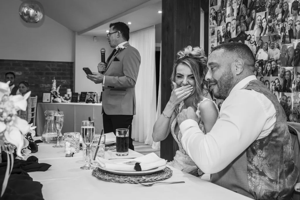 Bride laughing with her groom during wedding speeches at The Barn at Willerby Hill, East Yorkshire.